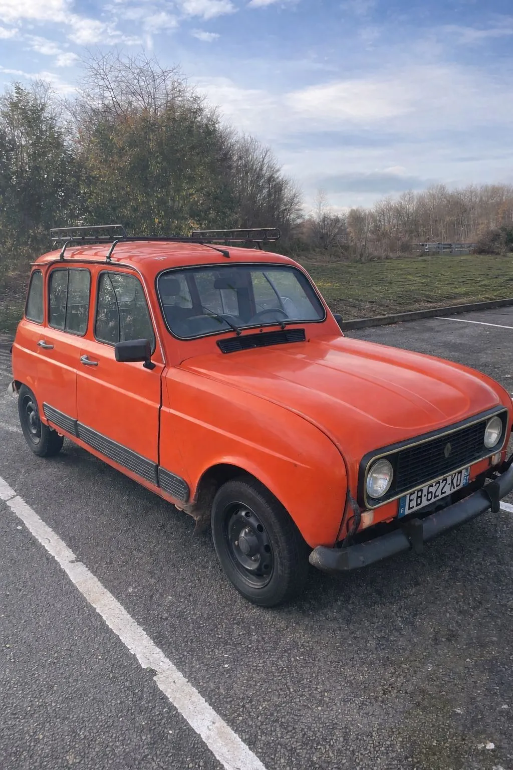 Notre Renault 4 GTL orange de 1986, garée sur un parking, avec sa galerie de toit